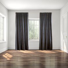 an empty room with wood floors and black curtains