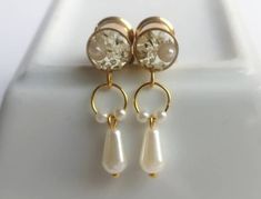 two pairs of earrings with pearls hanging from the end of each earring, on top of a white plate