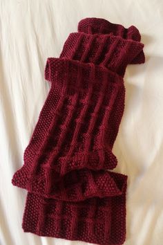 two red knitted scarfs laying on top of a bed