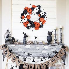 a decorated mantle with halloween decorations and candles on it in front of a white wall