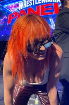 a woman with orange hair and sunglasses on