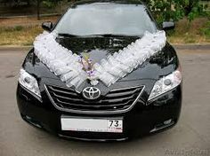 the car is decorated with white flowers and ribbons on it's headlight cover