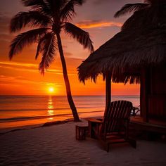 the sun is setting behind two palm trees on the beach with chairs under thatched umbrellas