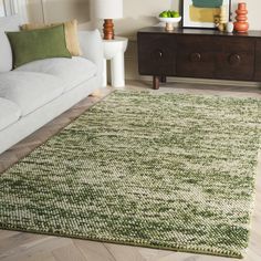 a living room with a white couch and green rug