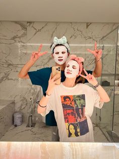 a man and woman are in the bathroom with their faces painted like they are making peace signs