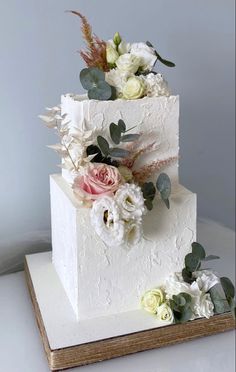 a white wedding cake with flowers and greenery