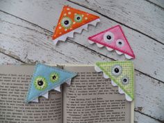 three felt pennants with eyeballs and eyes on them sitting next to an open book