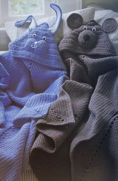 two crocheted animals wrapped in blankets on a bed