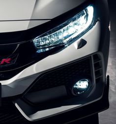 the front end of a white honda civic type car with its lights on and headlamps down