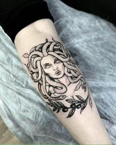 a woman's face with braids and leaves on her arm, done in black ink