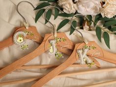 three wooden clothes hangers with floral designs on them next to white flowers and greenery