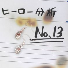 a pair of silver earrings sitting on top of a piece of paper with japanese writing