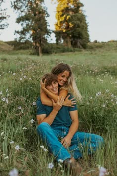 a man and woman sitting in the grass hugging