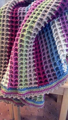 a multicolored crocheted blanket hanging from a hook