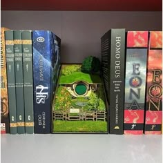 there is a book shelf with books and a miniature house in the middle of it