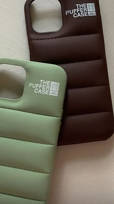 two cell phones sitting next to each other on top of a white surface with brown and green cases