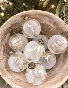 a wooden bowl filled with white and gold ornaments