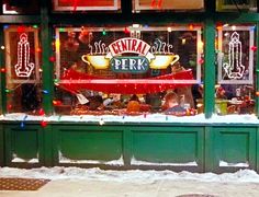 a store front with christmas lights on the windows and snow in the street below it