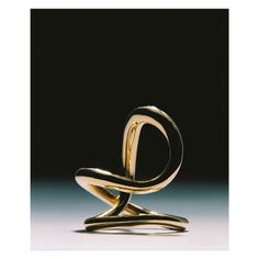 a gold ring sitting on top of a white table next to a black background with the letter o