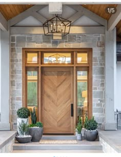 a wooden door with two planters on the steps and a chandelier above it