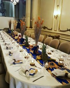 a long table is set up with place settings and pineapples on the plates