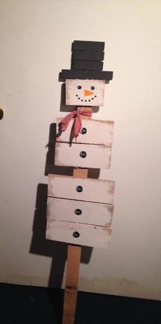 a snowman made out of wooden planks on top of a white wall next to a door