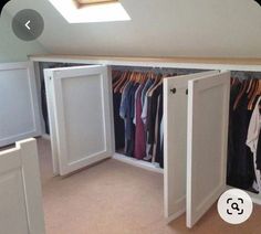 an attic closet with clothes hanging in it