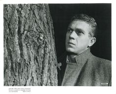 a man leaning against a tree with his head on the trunk and looking off into the distance