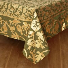 a green and gold table cloth on top of a wooden floor