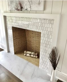 a white fireplace with a painting on the wall above it and a vase next to it