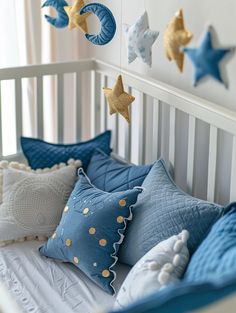 a crib bed with blue and gold stars hanging from the ceiling, along with decorative pillows