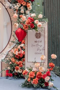 an arrangement of flowers and greenery is displayed on a table with a sign in the middle