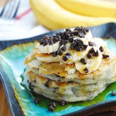 a stack of pancakes topped with chocolate chips and banana's on a blue plate