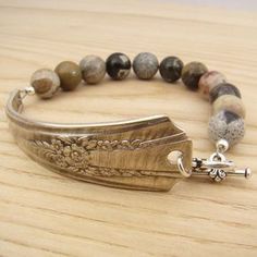 a bracelet with beads and a metal clasp on a wooden table next to a bead