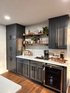 a kitchen with gray cabinets and white counter tops, an oven in the corner and shelves on the wall