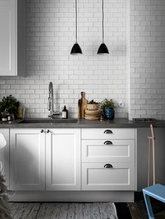 a kitchen with white cabinets and black pendant lights