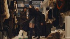 two people standing in front of a store filled with fur coats and other clothing items