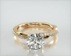 a rose gold engagement ring with a round diamond in the center and side stones on each band