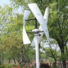 a white wind turbine sitting in the middle of a park