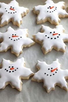 decorated cookies with frosting and snowman faces on a sheet of parchmented paper