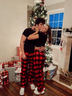 two people standing in front of a christmas tree