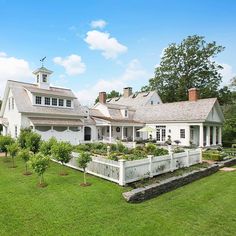 a large white house sitting on top of a lush green field