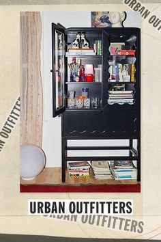 an open book shelf with books and other items in front of a curtained window