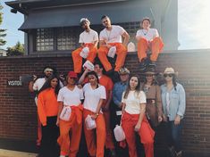 a group of people in orange jumpsuits posing for a photo outside the building