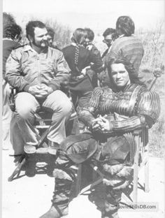 an old black and white photo of people sitting in chairs with their backs to each other