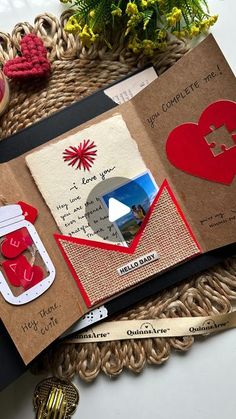 an open book with some red hearts on it and other items around the page,