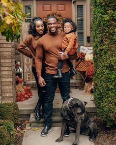 a man, woman and child standing on steps with a dog