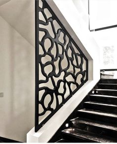 an iron stair railing on the side of a white wall next to some black and white stairs