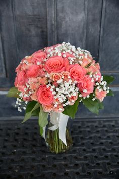 a bouquet of pink roses and baby's breath in a vase on a table