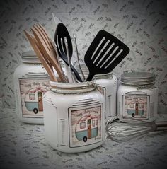 three jars with utensils and spoons in them sitting on a tablecloth